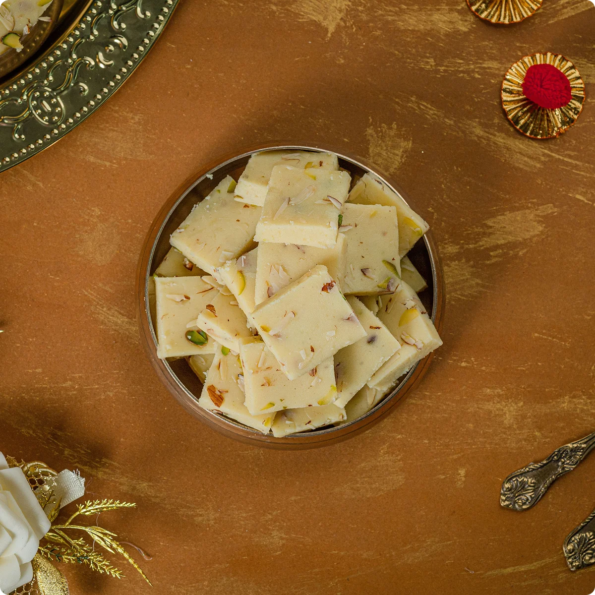 A brass bowl of traditional barfi